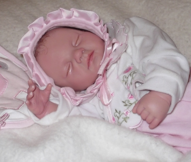 Baby reborn girl in sleeping position with closed eyes
