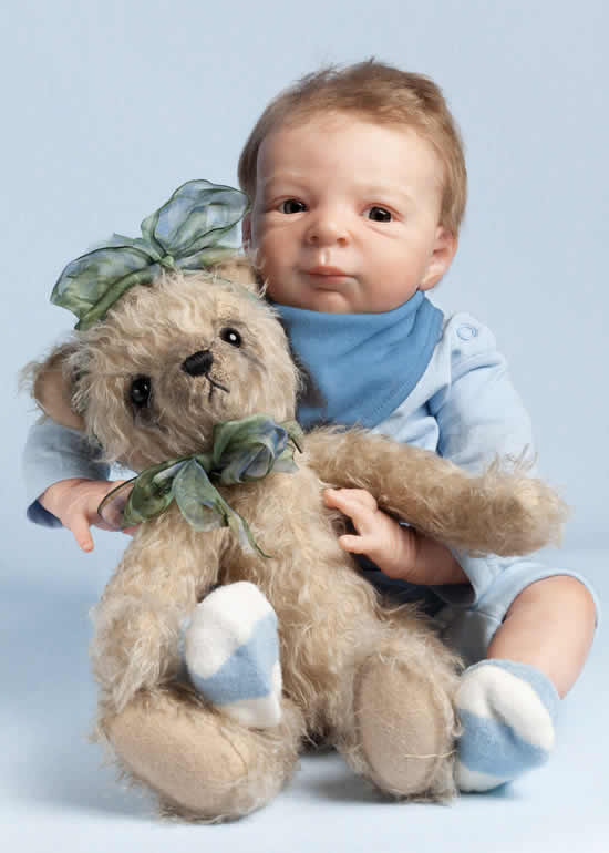 Reborn baby boy doll sitting up and holding a bear